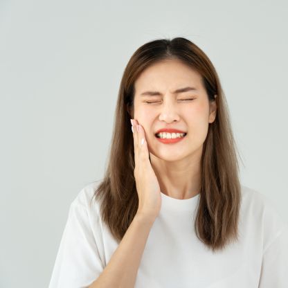 A woman holding her cheek from tooth pain