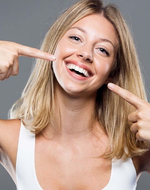 A woman pointing at her bright new smile