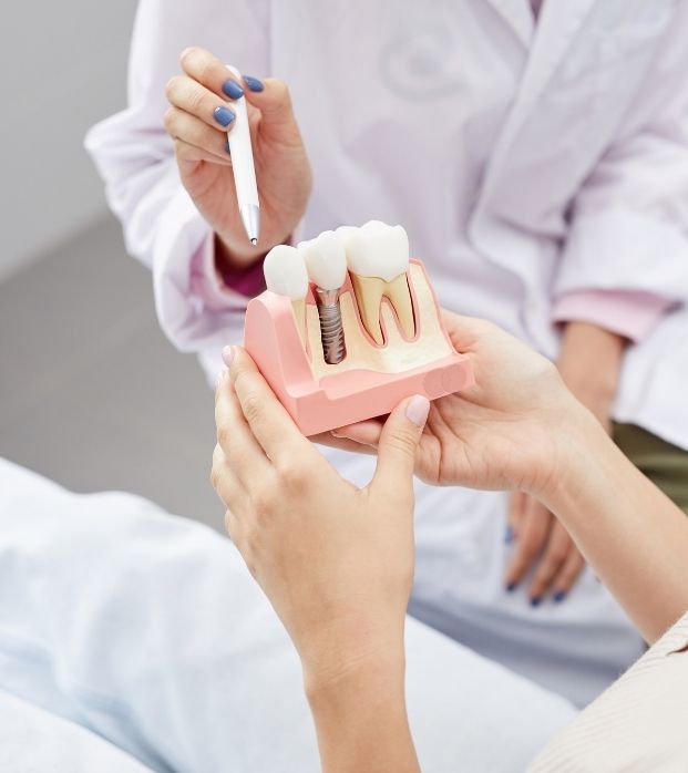 A dentist explaining a dental implant model to a patient