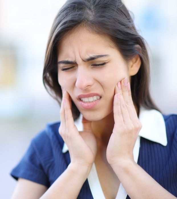 A woman holding her sore jaw