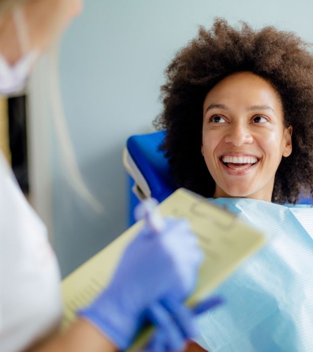 A new patient smiling in the dental chair during her exam